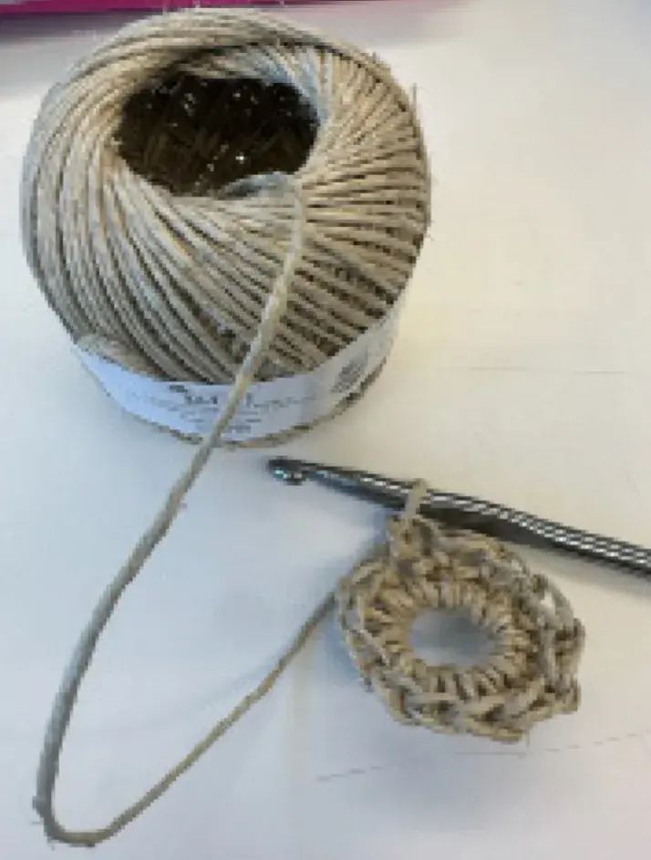 An in-progress sole, layers are starting to take shape but it is still incomplete and attached to the crochet hook.